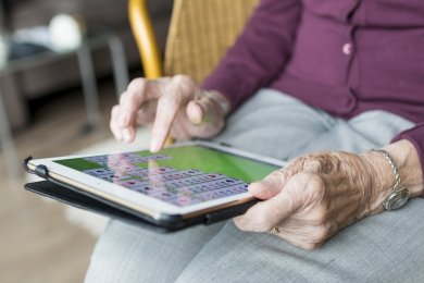 Seniorin spielt Karten auf einem Tablet
