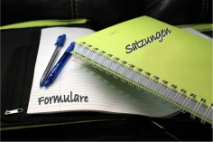 Ein Block Papier auf dem Formulare steht sowie ein Notizbuch, auf dem Fomulare steht