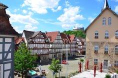 Marktplatz mit Fachwerkhäusern, dem Rathaus rechts und dem Schloss im Hintergrund